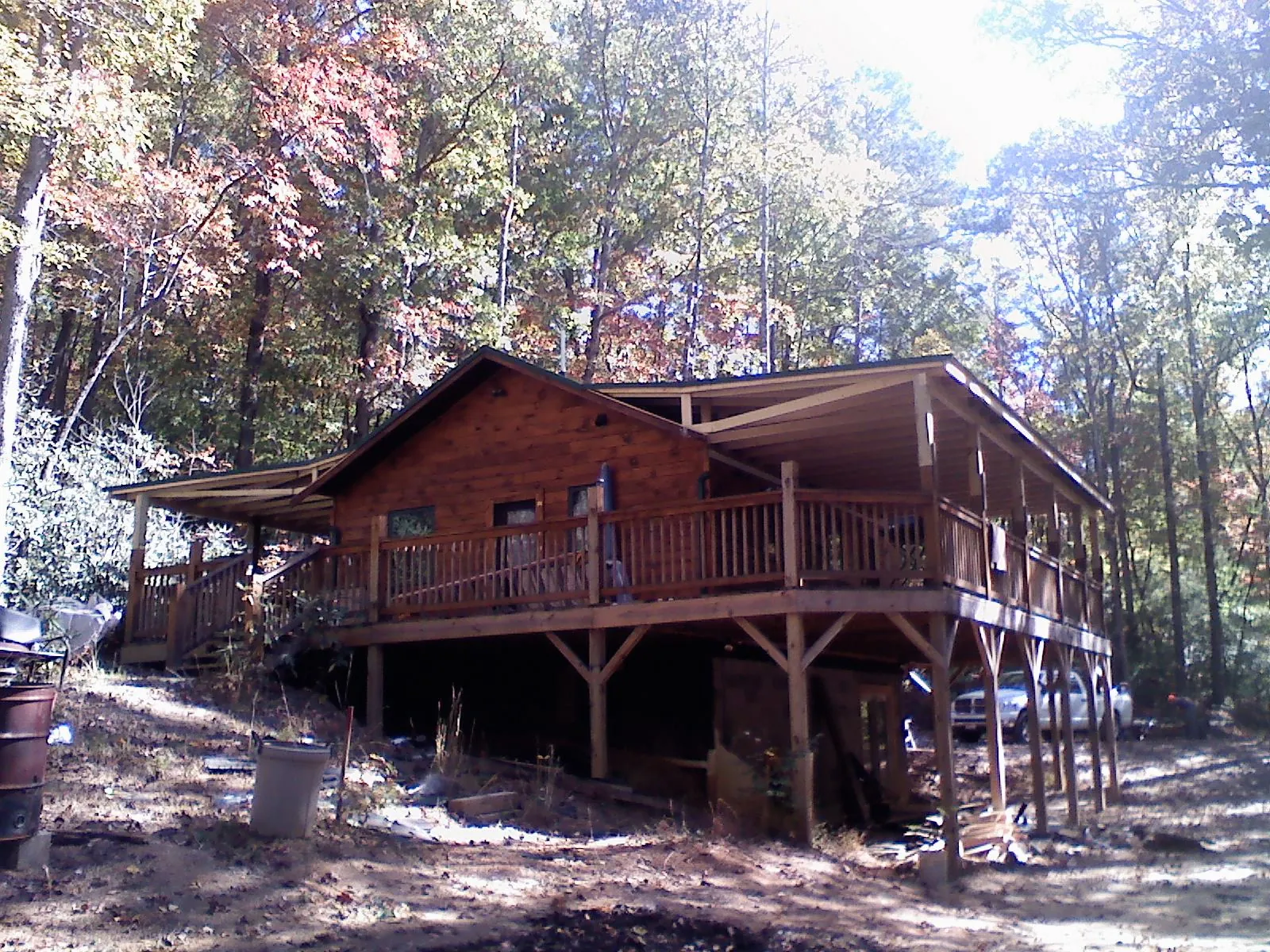 Log cabin with a wraparound porch and metal roof in the fall in Moore