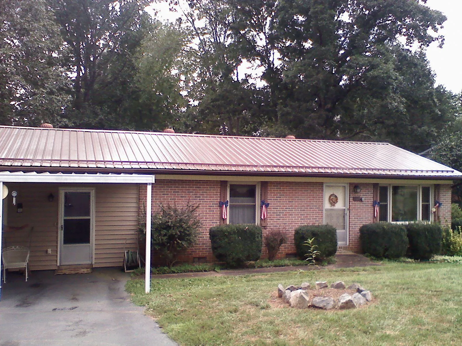 Bronze metal roof and carport on a brick ranch home — Roof Repair work by our crew in Moore